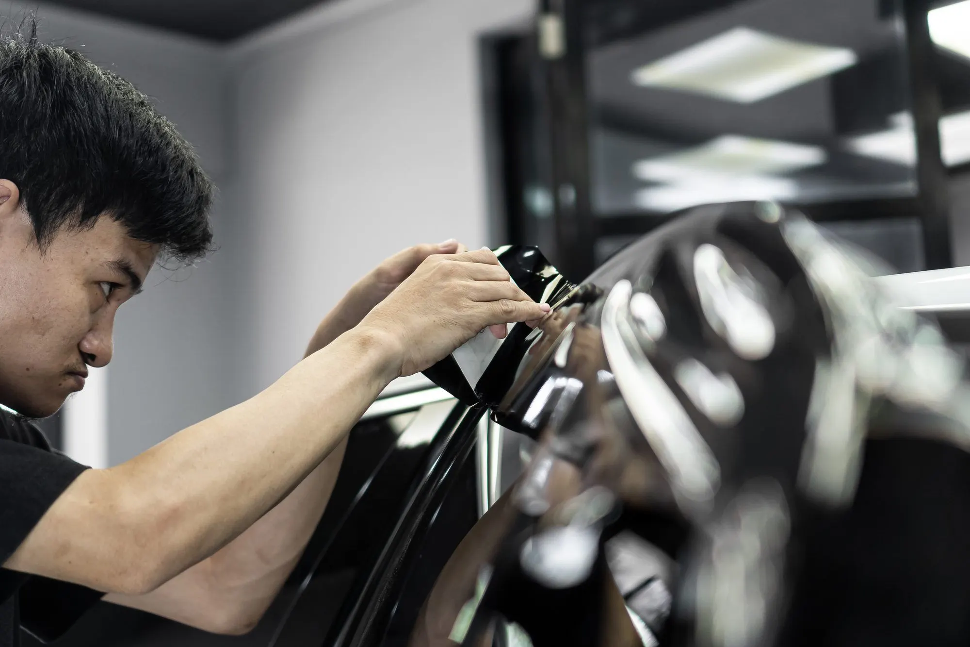 Teknisi First AutoWrap memasang film di pintu mobil hitam