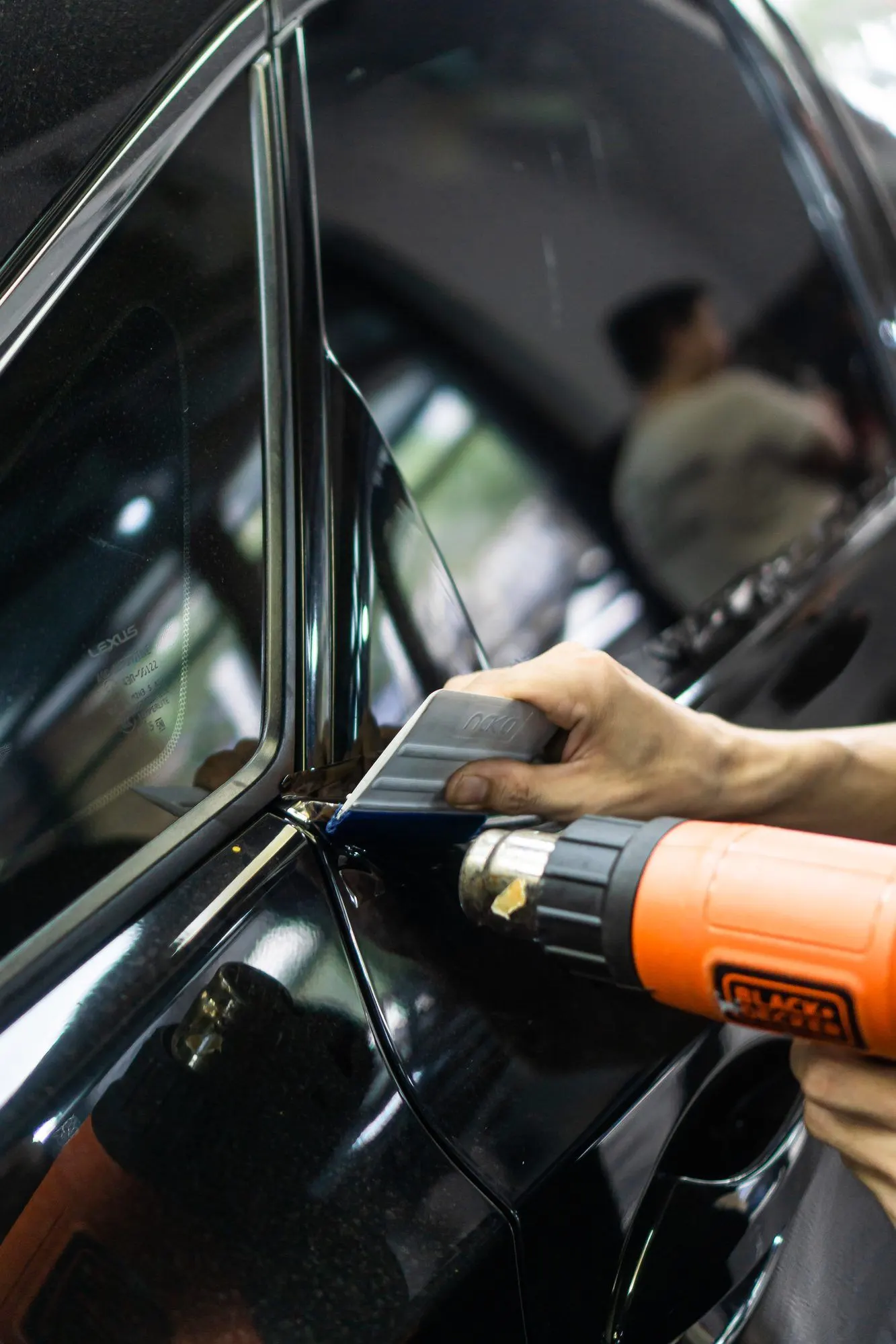 Film dipanaskan dengan heat gun di pilar mobil hitam